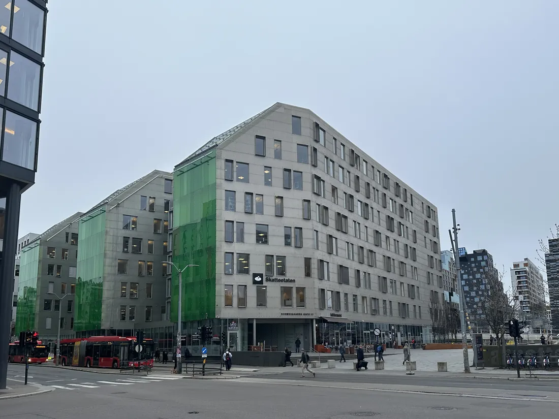 Skatteetatens kontorbygg i Schweigaards gate i Oslo sett fra gatekrysset, med navneskilt på fasaden og fotgjengere langt unna